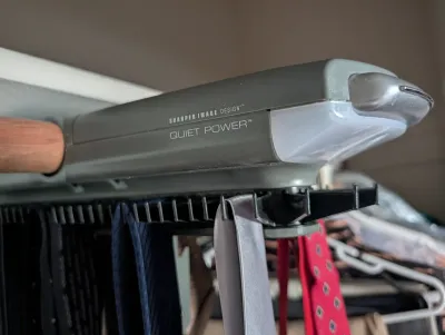 Sharper Image Design Quiet Power motorized tie rack, mounted on a closet rod and holding several neckties.  Ties sold separately.