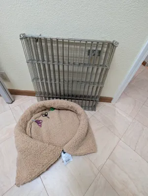 Collapsible metal wire pet crate panels shown with a plush tan fleece pet bed.