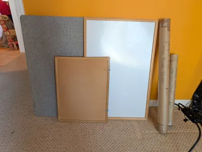 Assorted office and home decor items, including a gray fabric bulletin board, a wood-framed whiteboard, a smaller corkboard, and two...