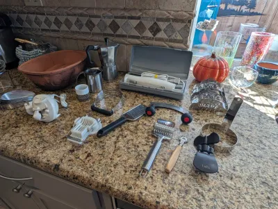 Assorted kitchen tools and gadgets, including an electric knife, moka pot, pastry blender, egg slicer, and various cutters, displayed on...