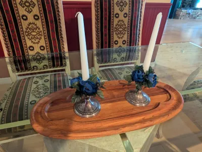 Pair of silver-plated candlesticks with blue floral accents and white taper candles, displayed on an oval wooden tray.