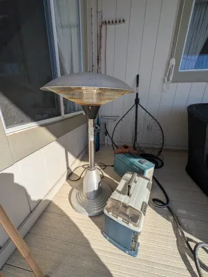 Electric patio heater with a dome top, shown alongside fishing gear including tackle boxes and a landing net.