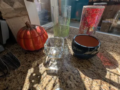 Assorted decorative glassware and ceramics, including a ceramic pumpkin lidded jar, a small square glass bowl, a dark glazed planter, and...