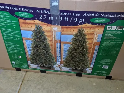 Boxed 9-foot artificial Christmas tree featuring multi-color and warm white LED lighting options.