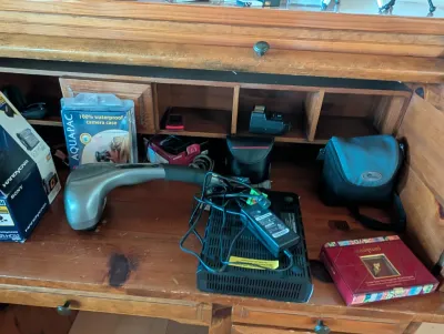Assorted electronics and accessories, including a handheld massager, a Sony Handycam box, an Aquapac waterproof camera case, and a small...
