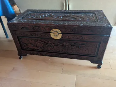 Vintage hand-carved camphor wood chest featuring intricate floral and bird motifs, complete with a decorative brass latch.