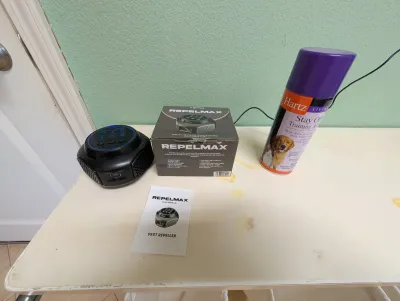 Repelmax ultrasonic pest repeller with its original box and user manual, shown alongside a can of Hartz Stay Off training aid spray.