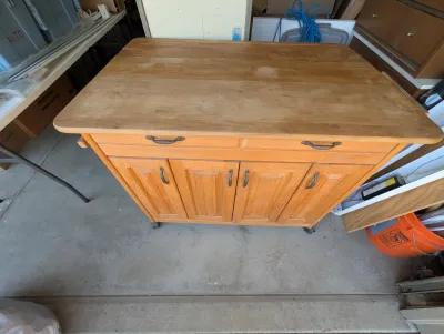 Wooden kitchen island cart on casters, featuring a drop-leaf countertop, two drawers, and four cabinet doors with metal hardware.