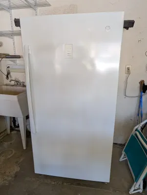 Modern GE white upright freezer featuring an external digital temperature control panel and a vertical handle.