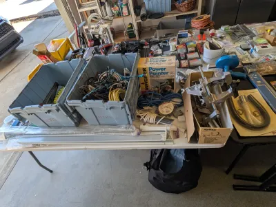 Assorted garage and workshop items, including a Wagner Power Painter, Zyliss vise, electrical cords in plastic bins, and various hardware...