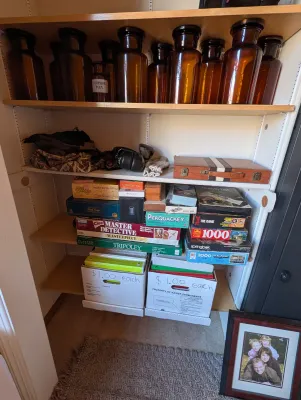 A collection of vintage amber glass apothecary jars, classic board games including Clue Master Detective and Tripoley, and various...