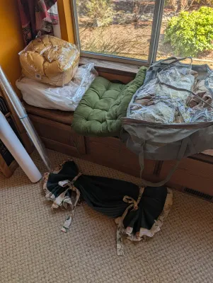 Assorted household textiles including a green tufted cushion, a yellow comforter in plastic packaging, and a large zippered storage bag...
