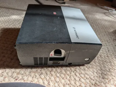 Vintage GAF Rotomatic slide projector with a black and silver housing, showing some surface wear and scratches.