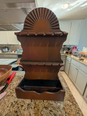 Vintage wooden wall-hanging pipe rack with a sunburst carved top, two slotted tiers for holding pipes, and a bottom drawer or tray.