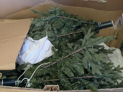Disassembled pre-lit artificial Christmas tree sections packed inside a cardboard storage box.