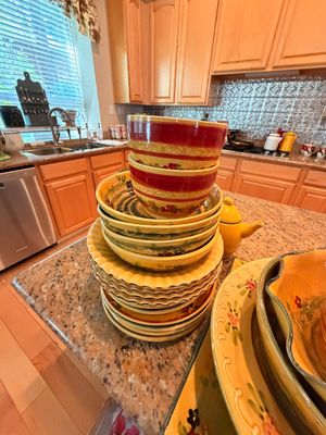 Sale Photo Thumbnail #9: Stack of hand-painted ceramic dinnerware featuring a rustic yellow and red floral pattern, including bowls and plates, displayed on a kitchen island.