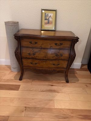 Sale Photo Thumbnail #2: Vintage French Provincial style bombe chest featuring three drawers with ornate metal pulls, hand-painted floral details, and carved cabriole legs.