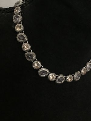 Sale Photo Thumbnail #184: A silver-tone costume jewelry necklace by Napier featuring alternating round and teardrop-shaped bezel-set rhinestones in shades of champagne and smoky purple/grey with textured border detailing. Includes an extender chain for adjustable length. Marked 'N
