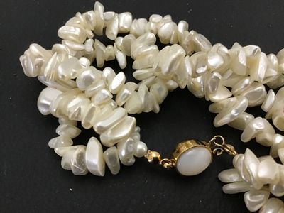 Sale Photo Thumbnail #124: Multi-strand freshwater pearl or mother-of-pearl chip/nugget necklace featuring a gold-toned clasp marked '14K TGF' (14K Gold Filled) with a cabochon accent insert. Clasp and strands appear intact and in good condition with minor vintage wear.