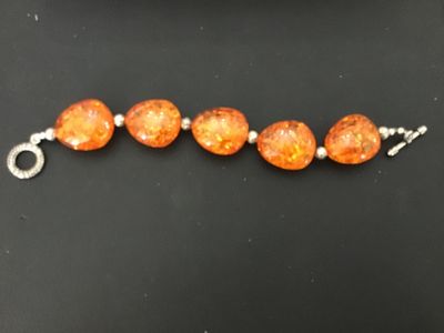 Sale Photo Thumbnail #11: Faux amber chunk bead statement bracelet featuring five large orange translucent, multi-faceted faux amber stones interspersed with textured silver-tone metal spacer beads. Finished with a decorative silver-tone toggle closure. Good condition with light s