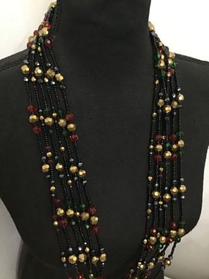 Sale Photo Thumbnail #208: Multi-strand statement necklace by Joan Rivers featuring layered strands of black seed beads interspersed with faceted metallic gold, deep red, and dark green beads. Includes a gold-tone lobster claw clasp with an adjustable extender chain and an oval Joa