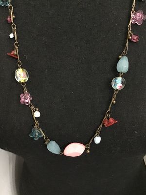 Sale Photo Thumbnail #115: Long brass-tone chain station necklace featuring a mix of colorful glass and acrylic beads, including floral charms, lampwork-style floral glass beads, faceted light blue drops, and pink cabochons. Good pre-owned condition with no visible damage.