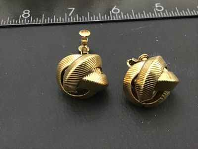 Sale Photo Thumbnail #268: Pair of vintage gold-tone clip-on earrings featuring a textured love knot design with combination screw-back and clip closures. Marked with patent number 2784478 (or similar) on the back. Each earring measures approximately 3/4 inch in diameter. Good vint