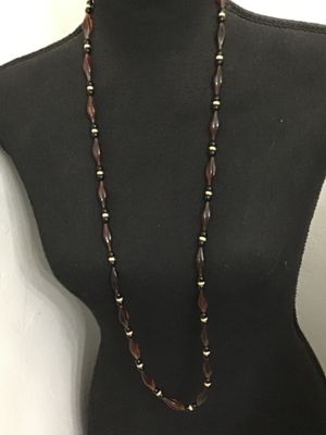 Sale Photo Thumbnail #170: Long vintage beaded strand necklace featuring amber-toned fluted/marquise acrylic beads alternating with black round beads and textured gold-tone spacers. Features a threaded barrel clasp closure. Measures approximately 30+ inches in length. In good vinta