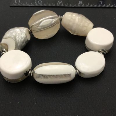 Sale Photo Thumbnail #87: A statement stretch bracelet featuring large, chunky art glass beads in opaque white, clear glass, and foil-lined accents. The beads come in various shapes including oval, round disc, and barrel forms, separated by small silvertone spacer beads. Good cond