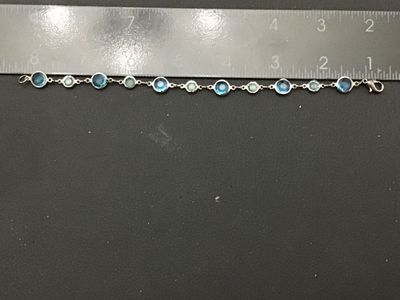Sale Photo Thumbnail #284: A silver-tone link station bracelet featuring alternating round bezel-set faceted crystals in dark blue and light green hues. The bracelet measures approximately 7.5 inches long and fastens with a lobster claw clasp. In good pre-owned condition with light