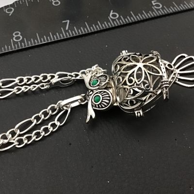 Sale Photo Thumbnail #81: Intricate silver-tone owl pendant with green faux stone/enamel eyes and an openwork filigree locket body that opens on a hinge. Attached to a silver-tone chain. Shows light general wear consistent with age and pre-owned use. Please see photos for detailed