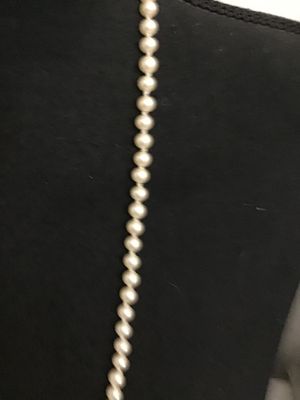 Sale Photo Thumbnail #141: A classic single strand faux or cultured pearl style necklace featuring hand-knotted construction between round cream-colored beads. Finished with a decorative silver-tone filigree marquise fishhook clasp. Overall good condition with minor vintage wear vi