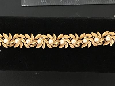Sale Photo Thumbnail #6: Vintage costume jewelry bracelet featuring brushed textured gold tone leaf links accented with round faux pearls throughout. Includes a fold-over clasp. Good vintage condition with light, age-appropriate wear.