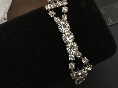 Sale Photo Thumbnail #38: Vintage silver-tone costume jewelry bracelet featuring a double strand of prong-set clear sparkling rhinestones with a central focal accent of larger round rhinestones. Features a fold-over clasp closure. Measures approximately 7 inches in length. In good