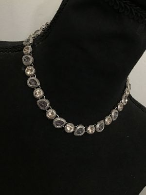 Sale Photo Thumbnail #185: A silver-tone costume jewelry necklace by Napier featuring alternating round and teardrop-shaped bezel-set rhinestones in shades of champagne and smoky purple/grey with textured border detailing. Includes an extender chain for adjustable length. Marked 'N