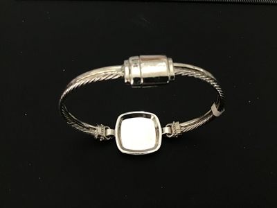 Sale Photo Thumbnail #30: Silver-tone twisted cable style cuff/bangle bracelet featuring a square center emblem with the initial 'E' set against an off-white enamel background, surrounded by a halo of clear rhinestones/crystals. Features a magnetic closure at the back. Light overa