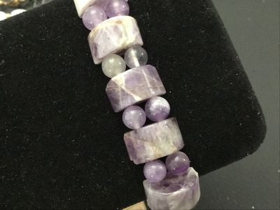Sale Photo Thumbnail #160: Natural gemstone stretch bracelet featuring polished rectangular/cylindrical purple chevron amethyst beads alternating with round accent beads. Features natural variations, veining, and matrix throughout the stones. Elastic band allows for easy wear. In g