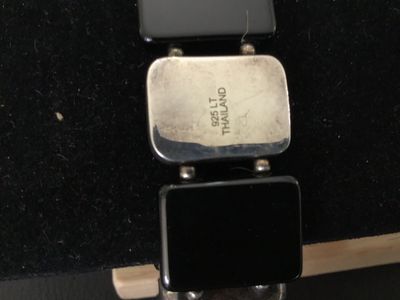Sale Photo Thumbnail #17: Sterling silver and black onyx panel bracelet featuring alternating rectangular sterling silver segments and smooth black onyx panels on a stretch cord. Marked '925 LT THAILAND' on the back of a silver panel. Shows minor tarnishing and surface wear consis