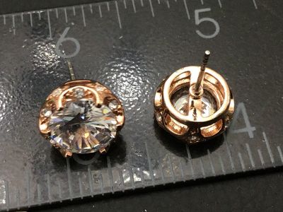Sale Photo Thumbnail #249: Pair of rose gold tone stud earrings featuring large faceted clear central crystals/rhinestones with halo accents. Each earring measures approximately 1/2 inch in diameter. Includes post backs. In good condition with bright sparkle and light wear consiste