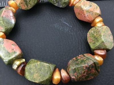 Sale Photo Thumbnail #43: A stretch beaded bracelet featuring large, faceted chunky unakite stone beads in green and pink hues, accented with smaller golden and amber-colored accent beads. Appears in good pre-owned condition with natural gemstone variations.