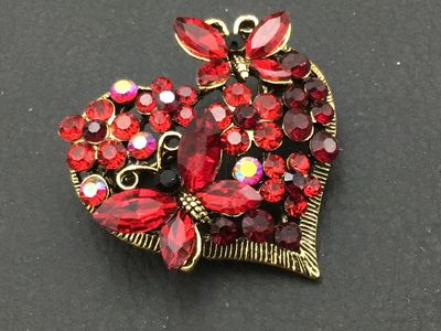 Sale Photo Thumbnail #253: Gold-tone heart-shaped brooch pin encrusted with red, dark red, and aurora borealis (AB) finish rhinestones, featuring butterfly motifs. Measures approximately 1.75 inches wide. Excellent pre-owned condition with all stones intact and functional rollover 
