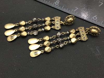 Sale Photo Thumbnail #279: Pair of ornate gold-tone dangle earrings featuring multi-strand drop chains with faceted dark crystal beads and hammered teardrop charms. Pierced post backings. Measure approximately 2.5 to 3 inches long. Good condition with no missing beads or visible da