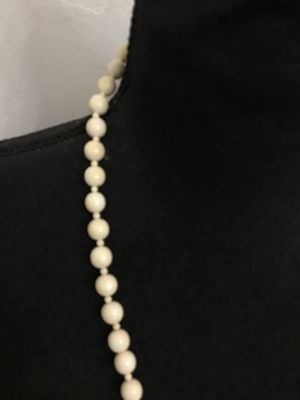 Sale Photo Thumbnail #139: A vintage cream-colored beaded necklace featuring a hand-carved focal element shaped like a ram or goat head hooked onto an oval loop. Made of carved bone, faux ivory, or composite resin beads strung together. Good condition with light vintage wear.