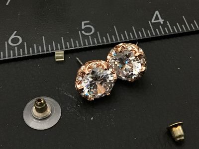 Sale Photo Thumbnail #247: Pair of rose gold tone stud earrings featuring large faceted clear central crystals/rhinestones with halo accents. Each earring measures approximately 1/2 inch in diameter. Includes post backs. In good condition with bright sparkle and light wear consiste