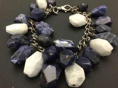 Sale Photo Thumbnail #143: A striking  925 chunky charm-style bracelet featuring large, faceted natural stone beads in shades of deep blue sodalite and white quartz or moonstone. The stones are attached to a silver-tone chain with a lobster claw clasp. The clasp appears to have fai