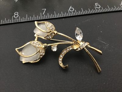 Sale Photo Thumbnail #287: Gold-tone floral brooch featuring two tulip blossom motifs set with translucent milky white/faux moonstone cabochons and accented with clear rhinestones. Measures approximately 2 inches in length. Features a rollover safety clasp on the back. Good vintage