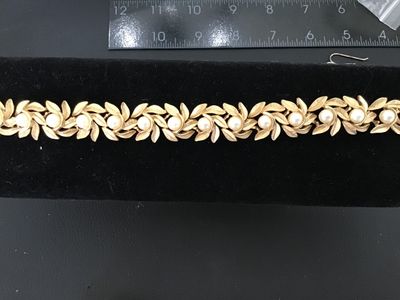 Sale Photo Thumbnail #8: Vintage costume jewelry bracelet featuring brushed textured gold tone leaf links accented with round faux pearls throughout. Includes a fold-over clasp. Good vintage condition with light, age-appropriate wear.