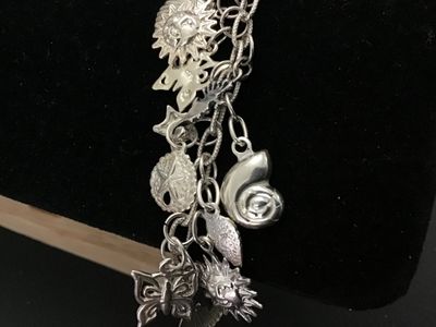 Sale Photo Thumbnail #47: A sterling silver charm bracelet featuring various celestial and aquatic/nautical themed charms including suns, butterflies, seashells, starfish, and sand dollars. Multiple charms are marked '925' for sterling silver quality. Features a lobster claw clasp