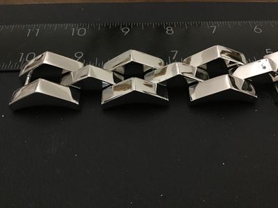 Sale Photo Thumbnail #177: Bold modern silver-tone wide link bracelet featuring stylized chevron/peak top panels with textured open undersides and a fold-over clasp. Features a small heart symbol stamped near the clasp. Bracelet measures approximately 7.5 to 8 inches in length and 