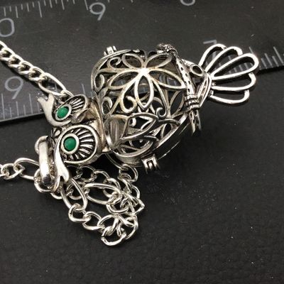 Sale Photo Thumbnail #78: Intricate silver-tone owl pendant with green faux stone/enamel eyes and an openwork filigree locket body that opens on a hinge. Attached to a silver-tone chain. Shows light general wear consistent with age and pre-owned use. Please see photos for detailed